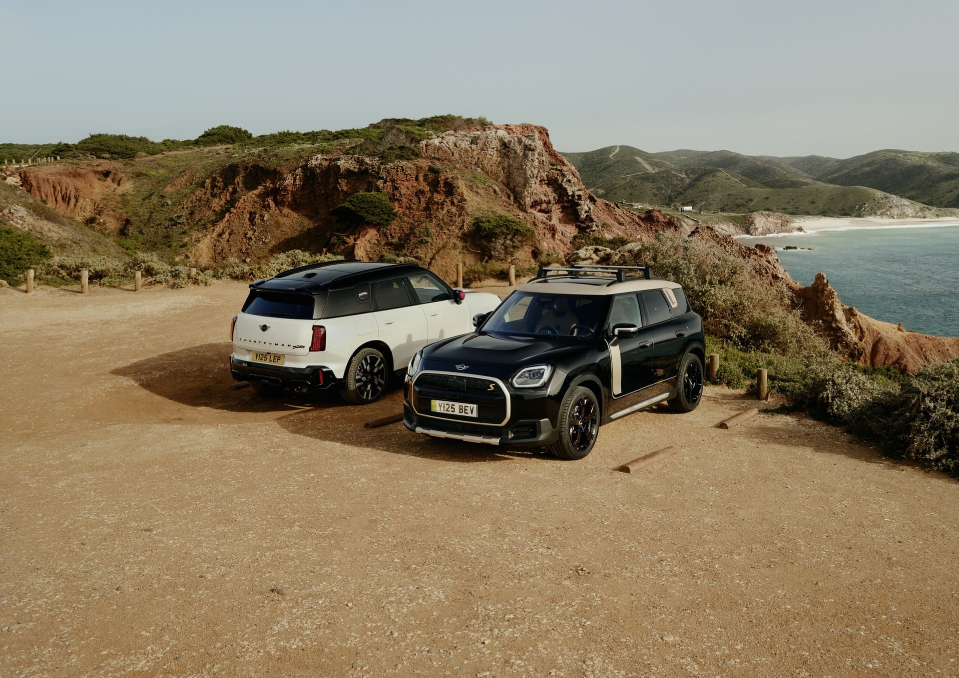 Dois MINI Countryman Elétricos estacionados ao pé da praia.